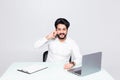 Businessman sitting at table in office hall, talking on mobile phone and using laptop Royalty Free Stock Photo