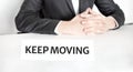 Businessman sitting at the table and signboard with text KEEP MOVING