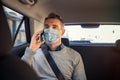 Businessman sitting in a taxi while talking over phone with mask Royalty Free Stock Photo