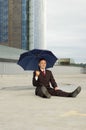 Businessman sitting with umbrella