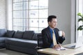 Businessman sitting on workplace drinking coffee while working at his desk. Handsome businessman working on laptop in his workstat Royalty Free Stock Photo