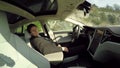 Deeply asleep businessman behind the steering wheel in self-driving electric car
