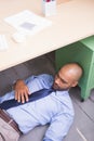 Businessman sleeping under desk Royalty Free Stock Photo