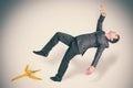 Businessman slipping and falling from a banana peel Royalty Free Stock Photo