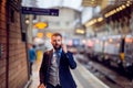 Businessman with smartphone, making a phone call, train platform Royalty Free Stock Photo