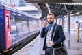 Businessman with smartphone, making a phone call, train platform Royalty Free Stock Photo