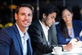 Businessman smiling at camera while colleagues interacting in the background Royalty Free Stock Photo