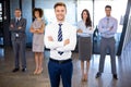 Businessman smiling at camera while his colleagues standing in background Royalty Free Stock Photo