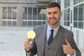 Businessman smiling while holding a big coin Royalty Free Stock Photo