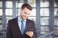 Businessman smiling while looking at mobile phone Royalty Free Stock Photo