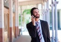 Businessman smiling and talking on mobile phone in town Royalty Free Stock Photo