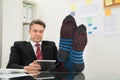 Businessman With Socks In His Feet Using Digital Tablet