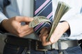 Businessman with stack of one hundreds US dollar in hands, analysing profit