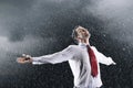 Businessman standing arms spread facing incoming rain Royalty Free Stock Photo