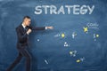 Businessman standing as if he is going to punch near the dark blue wall with an action plan drawn on it. Royalty Free Stock Photo