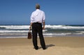 Businessman standing on beach relaxing looking at horizon, retirement planning concept Royalty Free Stock Photo