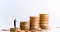 Businessman standing on coin stack.