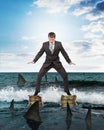 Businessman standing on coins above sharks Royalty Free Stock Photo