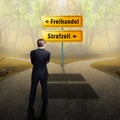 Businessman standing at a crossroad having to decide between `free trade ` and `tariff ` with road signs in German Royalty Free Stock Photo