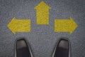 Businessman standing in front of three arrows on asphalt road,