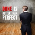 Businessman standing in front of a wall with the message `Done is better than perfect `