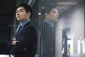 Businessman standing by glass wall, reflection Royalty Free Stock Photo