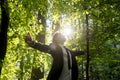 Businessman standing with his arms outspread in woodland