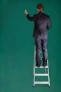 Businessman Standing On Ladder Writing On Chalkboard Royalty Free Stock Photo