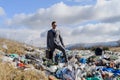 Businessman standing on landfill, large pile of waste. Consumerism versus pollution concept. Corporate social Royalty Free Stock Photo