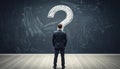 Businessman standing before large question mark on blackboard symbolizing uncertainty, decision making, problem solving and the Royalty Free Stock Photo
