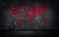 Businessman standing and looking to red world map on concrete wall.