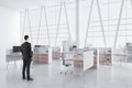 Businessman standing in modern concrete coworking office interior with panoramic window and city view, equipment, daylight and Royalty Free Stock Photo