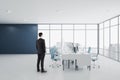 Businessman standing in modern concrete coworking office room interior with panoramic window with city view, equipment, daylight Royalty Free Stock Photo