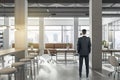 Businessman standing in modern coworking office interior with bright city view and concrete flooring. Design and workplace style Royalty Free Stock Photo