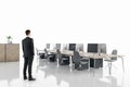 Businessman standing in modern white coworking office interior with computers, equipment, reception desk, wooden furniture and Royalty Free Stock Photo