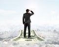 Businessman standing on money flying carpet watching the front