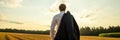 Businessman standing in nature under evening sky looking in to the distance with his suit jacket over his Royalty Free Stock Photo