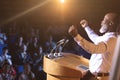 Businessman standing near podium and giving speech to the audience in the auditorium