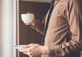 Businessman standing near window and holding coffee cup relax while working Royalty Free Stock Photo