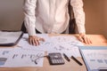 Businessman standing in office with papers laid on the table. Concerns and business planning.