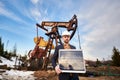 Businessman standing on an oilfield holding mini solar module next to an oil rig Royalty Free Stock Photo