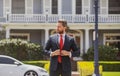 Businessman standing outside a modern house. Real estate concept. Agent ready to sell home. Royalty Free Stock Photo