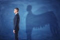 Businessman is standing in profile and casting a shadow of angel wings on blue chalkboard background