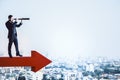 Businessman standing on red arrow and using binoculars Royalty Free Stock Photo