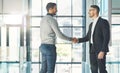 Businessman standing, smiling and with a handshake, greets a colleague in an office. Executive meets client or partner Royalty Free Stock Photo