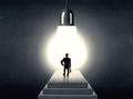 Man standing on a step in front of a huge light bulb Royalty Free Stock Photo