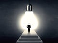 Man standing on a step in front of a huge light bulb Royalty Free Stock Photo