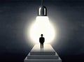 Man standing on a step in front of a huge light bulb Royalty Free Stock Photo