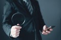 Businessman standing in suit holding magnifying glass and smartphone.Search and research concept Royalty Free Stock Photo