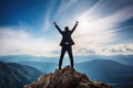 Businessman standing on top of a mountain with his arms raised celebrating success Royalty Free Stock Photo